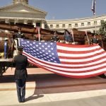US flag held in front of steel wreckage from the 9/11 tragedy
