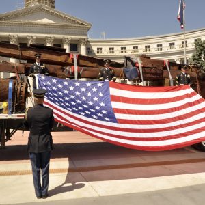 US flag held in front of steel wreckage from the 9/11 tragedy
