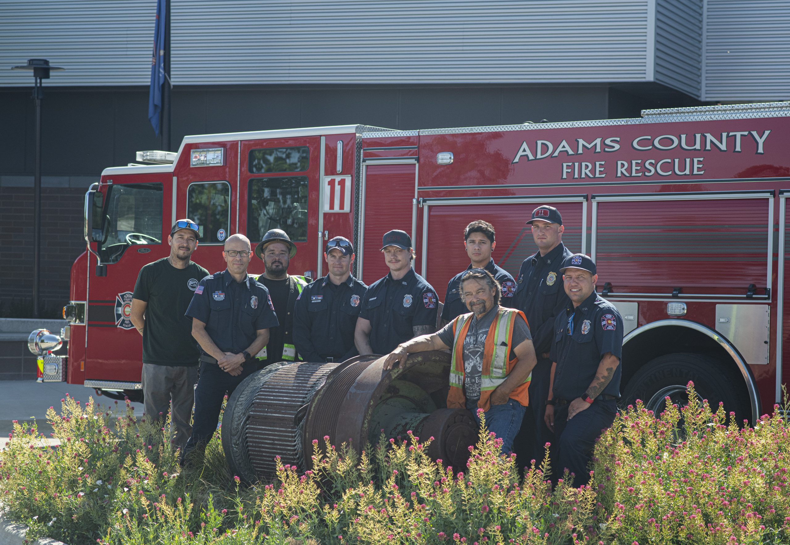 Men standing in front of a fire truck with a piece of World Trade Center steel